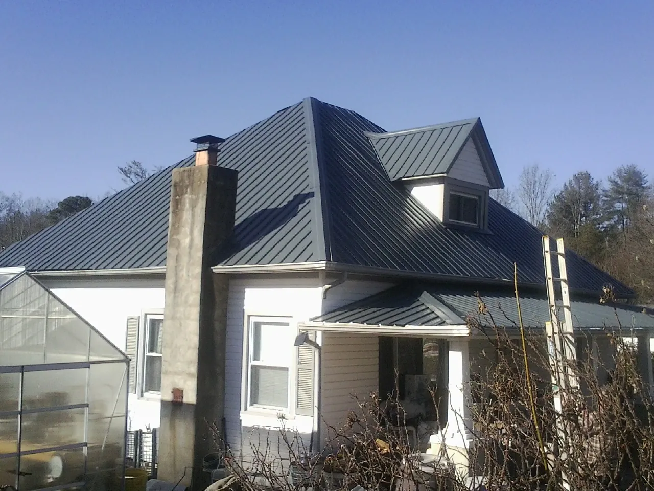 Dark blue standing seam metal roof on a white farmhouse with dormer in South Saint Paul