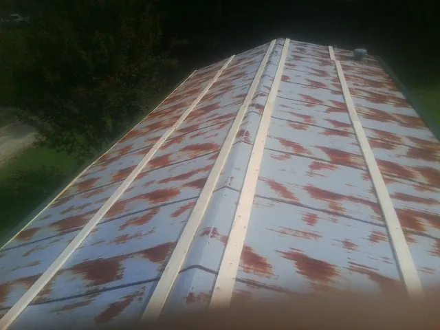 Rusted metal roof panels with new wood purlins before replacement — Storm Damage Roof Repair in South Saint Paul by Roofing Brothers
