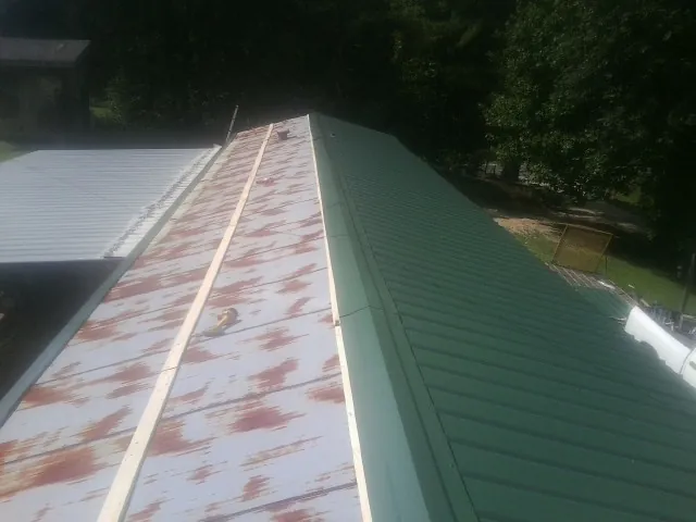 Old rusted panels beside newly installed green metal roofing — Wind Damage Roof Repair by Roofing Brothers in South Saint Paul