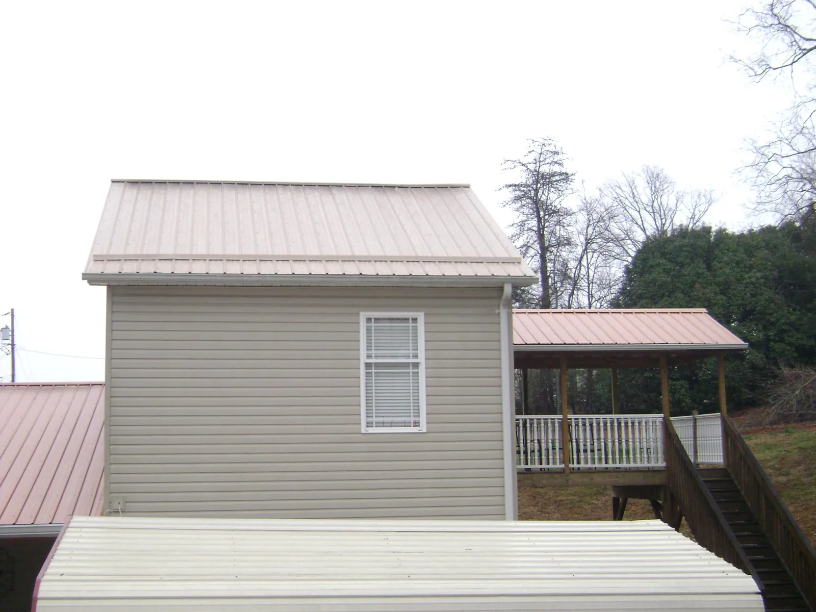 Tan metal roofs on a two story addition and attached porch, from a Roof Replacement job in South Saint Paul