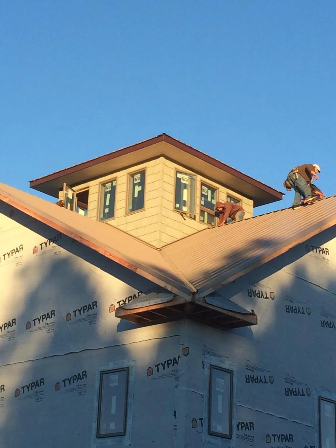 Roofers working around a rooftop cupola on a new metal roof at sunset — Roof Waterproofing in South Saint Paul by Roofing Brothers